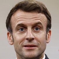 Emmanuel Macron lève l'index en regardant fixement au loin.