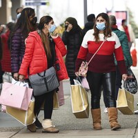 Deux femmes tenant des sacs de magasinage à l'extérieur d'un centre commercial.