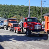Des camionneurs et des camions stationnés se trouvent devant les bureaux de Gaspé du ministère des Transports du Québec.