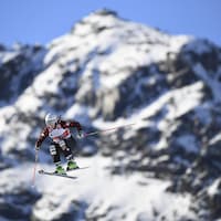 Le skieuse canadienne Marielle Thompson dans les airs pendant une épreuve de ski cross. En arrière-plan, une montagne enneigée. 