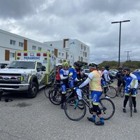 Des cyclistes sont sur leur vélo près d'un véhicule ambulancier. 
