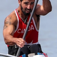 Un homme dans son embarcation avec une rame qui participe à une course de paracanoë-kayak.
