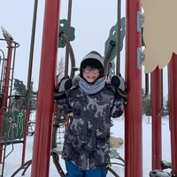 Mathis regarde la caméra à partir d'un module jeu dans un parc.