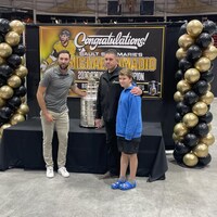 Michael Amadio pose la coupe Stanley et deux personnes.