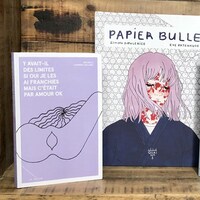 Les trois livres sont posés, debout, dans une caisse de bois.