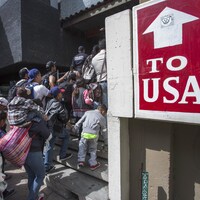 Des migrants font la file devant un immeuble.