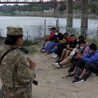 Des migrants surveillés par des membres de la Garde nationale américaine.