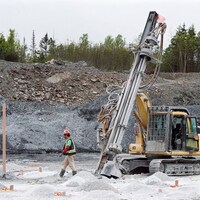 Un travailleur marche sur le site de la mine d'or Touquoy en Nouvelle-Écosse à côté d'une machine.