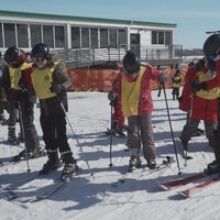 Des membres de la Patrouille canadienne de ski de Qu'Appelle enseignent les rudiments du ski à des enfants. 