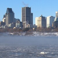 De la fumée s'échappe du fleuve Saint-Laurent avec des immeubles montréalais en arrière-plan.