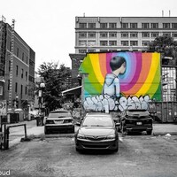 Une photo de la ville en noir et blanc avec une murale en couleur d'un homme tourné vers le mur.