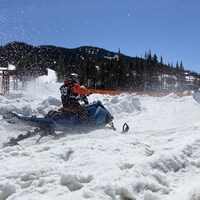 Une motoneige fait lever de la neige sur un parcours.