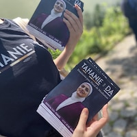 Une femme tient deux piles de dépliants de campagne de Tahanie Aboushi.