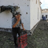 Un homme âgé passe devant un bâtiment détruit par un bombardement.