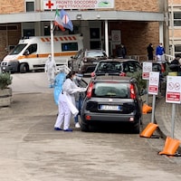 Des travailleurs de la santé près d'une voiture.