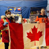 Natalia Kusendova et un membre de son équipe tiennent un drapeau canadien.