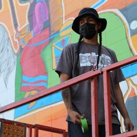 L'artiste Nathan Meguinis devant sa murale à Calgary.