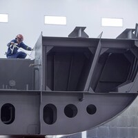 Une image montre un employé du chantier naval Irving à Halifax qui travaille sur une section d'un navire extracôtier et de l'Arctique devant être livré à la Marine royale canadienne.