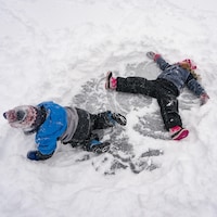 Deux enfants s'amusent sur la glace et la neige.