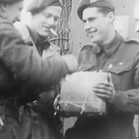 Des soldats souriants ouvrent un cadeau de Noël.