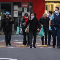 Des gens sont escortés par la police à la sortie d'un supermarché d'Auckland, en Nouvelle-Zélande.