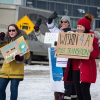 Un groupe de personnes manifeste à une intersection du centre-ville d'Iqaluit à l'occasion du Jour de la Terre, le 22 avril 2022.