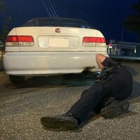 Un policier couché par terre est en train de regarder sous une voiture modifiée.