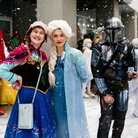 Trois personnes costumées en personnage d'Elsa, d'Anna et de Mandalorien sous la neige.