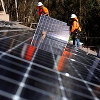 Des travailleurs installent des panneaux solaires sur un toit.