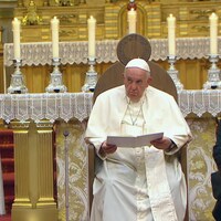 Assis sur son siège, devant l'autel, le pape François écoute les mots de bienvenue de Mgr Raymond Poisson.