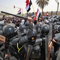 Des policiers essaient de contenir une foule près du parlement irakien.
