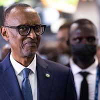 Paul Kagame en plan rapproché et deux hommes derrière lui.