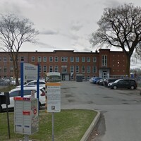 L'édifice est visible à partir de la rue. On voit un stationnement en premier plan.