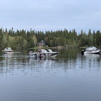Deux bateaux se déplacent sur un lac près de Val-d'Or. D'autres sont immobiles au quai.