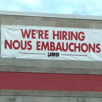 Une affiche indiquant "Nous embauchons" sur le bâtiment d'une entreprise.