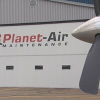 Une hélice d'avion devant un garage de Planet-Air Maintenance