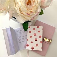 Des carnets de notes placés sur une table, près d'un bouquet de fleurs.