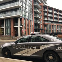 Photo d'une autopatrouille grise devant un immeuble en briques brunes.