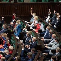 Des députés lèvent la main dans l'enceinte d'un parlement.