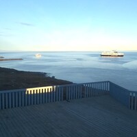 Un bateau et deux navires se trouvent au large devant le Centre des visiteurs Nattinak à Pond Inlet.
