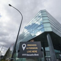 Une personne portant une pancarte devant les bureaux de Pornhub.