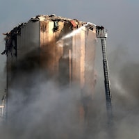 Des pompiers libanais tentent d’éteindre le feu dans le port de Beyrouth.