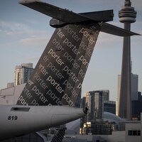 La queue d'un avion de Porter devant la tour CN et le centre-ville de Toronto.