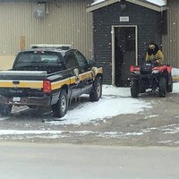 Un homme sur un véhicule tout-terrain est stationné devant la porte du poste de police de Kuujjuarapik.