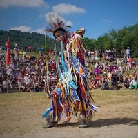 Sylvain Guay, vêtu d'un costume traditionnel autochtone, danse.