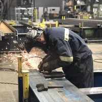 Le travailleur est en train de souder une pièce d'acier dans une usine.