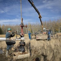 Un ouvrier utilise de la machinerie lourde près d'un puits.