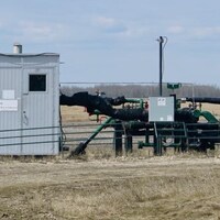 Le puits de gaz naturel dans la propriété de James Kirstein est une petite maison en tôle avec des tuyaux qui en ressortent dans un champ.