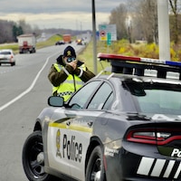 Un policier sur le bord de l'autoroute tient un radar.                  