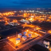 Photo prise par drone d'une raffinerie de pétrole illuminée au crépuscule.